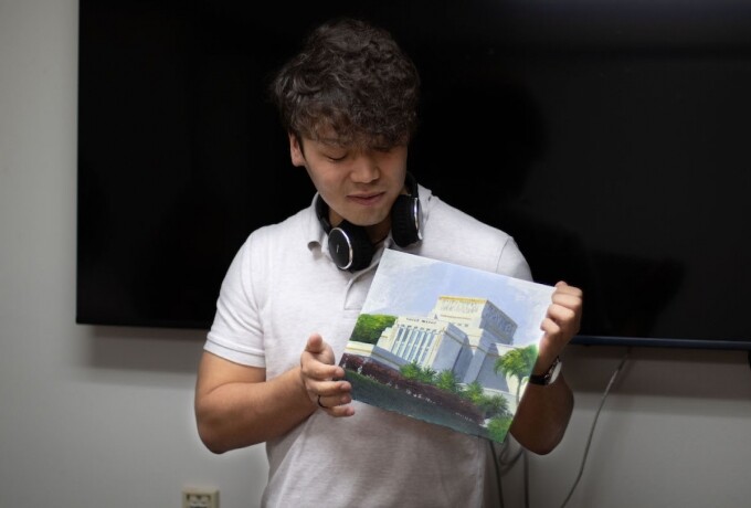 A man is holding a painting of the Laie Hawaii Temple