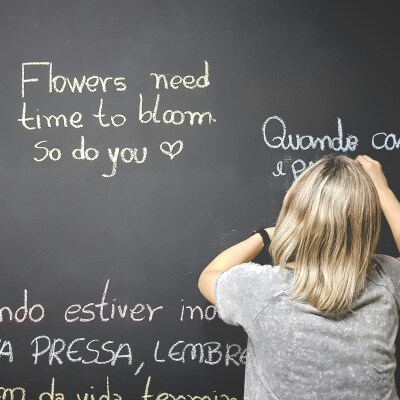 woman writing different languages on chalkboard