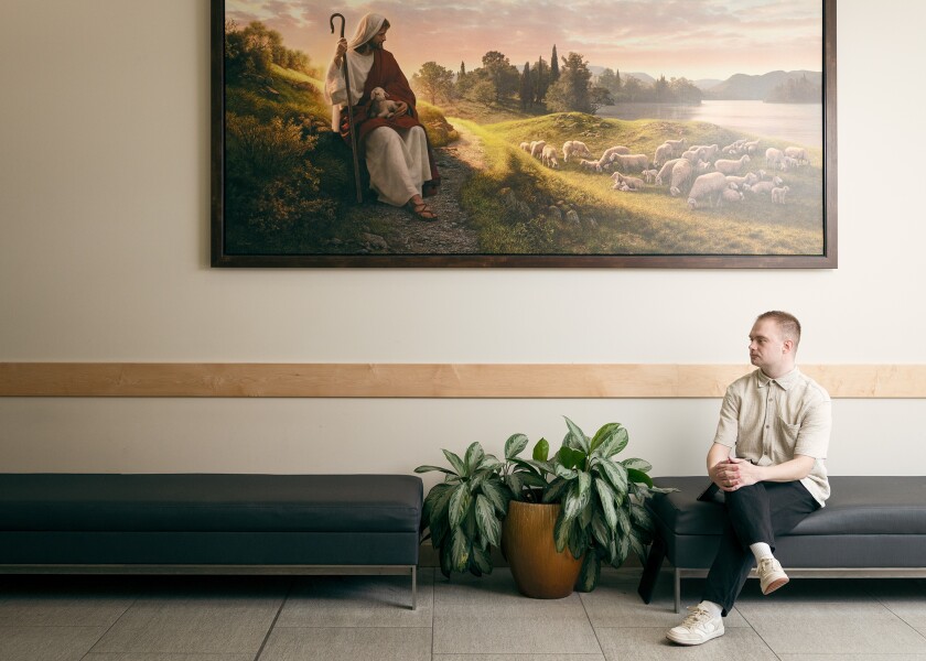 A young man sits underneath a painting of jesus christ
