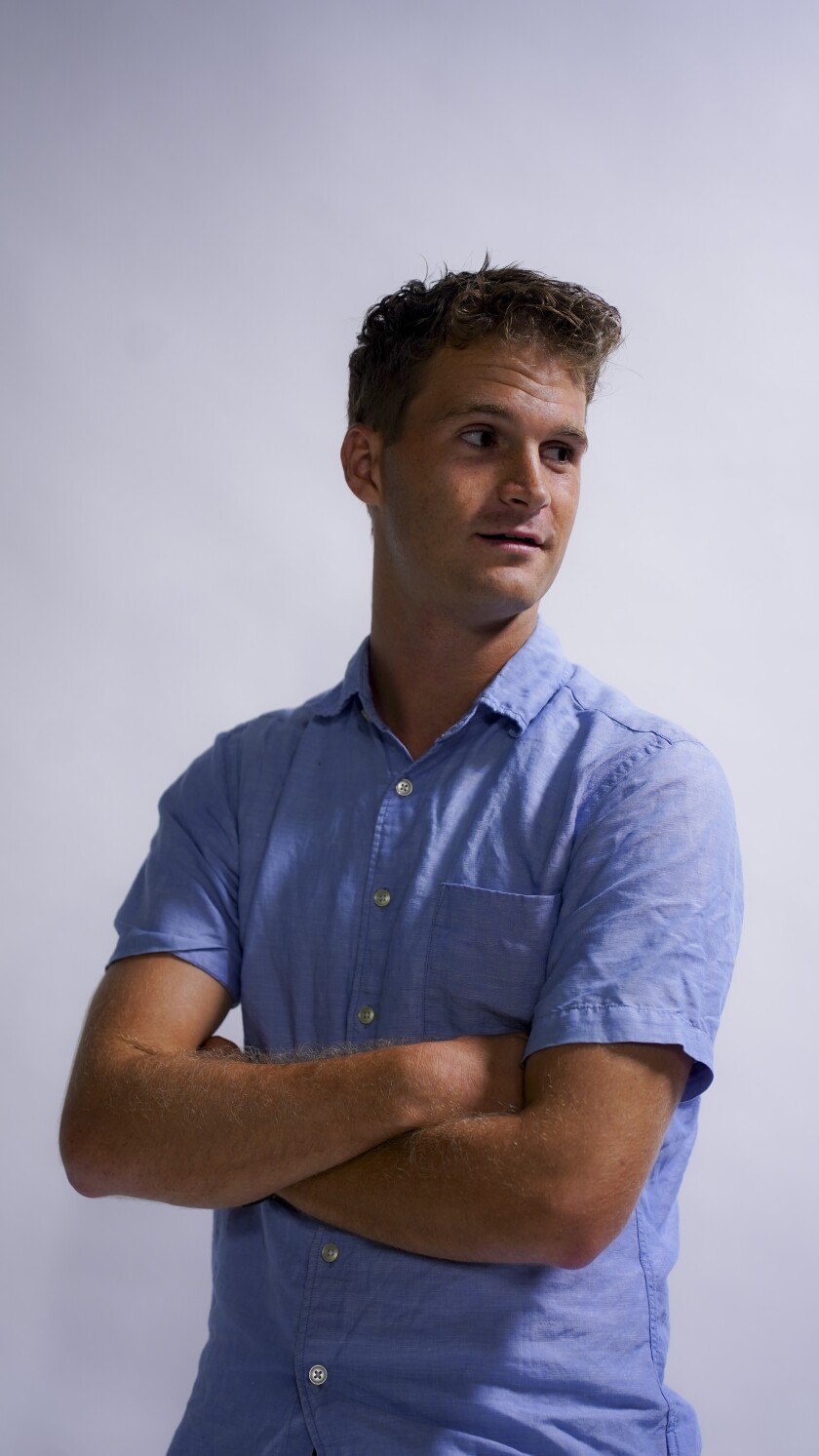 A man folds his arms and looks off to the side of the camera.