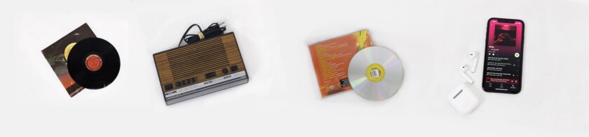 Various music technology laid out on a white background, including an iPhone with air pods, a CD with a bright orange and yellow case, a record with a black, green and red case and a cassette tape player.