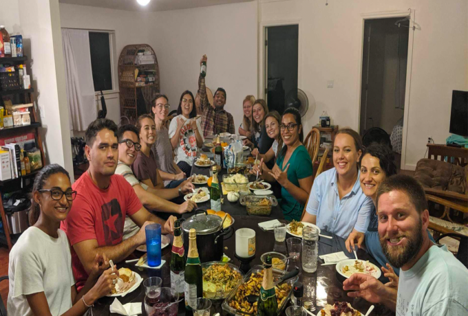 A group of friends sits around a table full of food for Canadian Thanksgiving