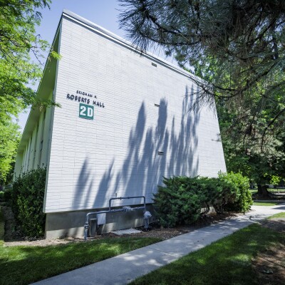 Exterior of a Wymount Terrace apartment building with shaded walkways, balconies, and surrounding trees and bushes.