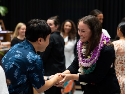 A woman shakes the hand of a young man