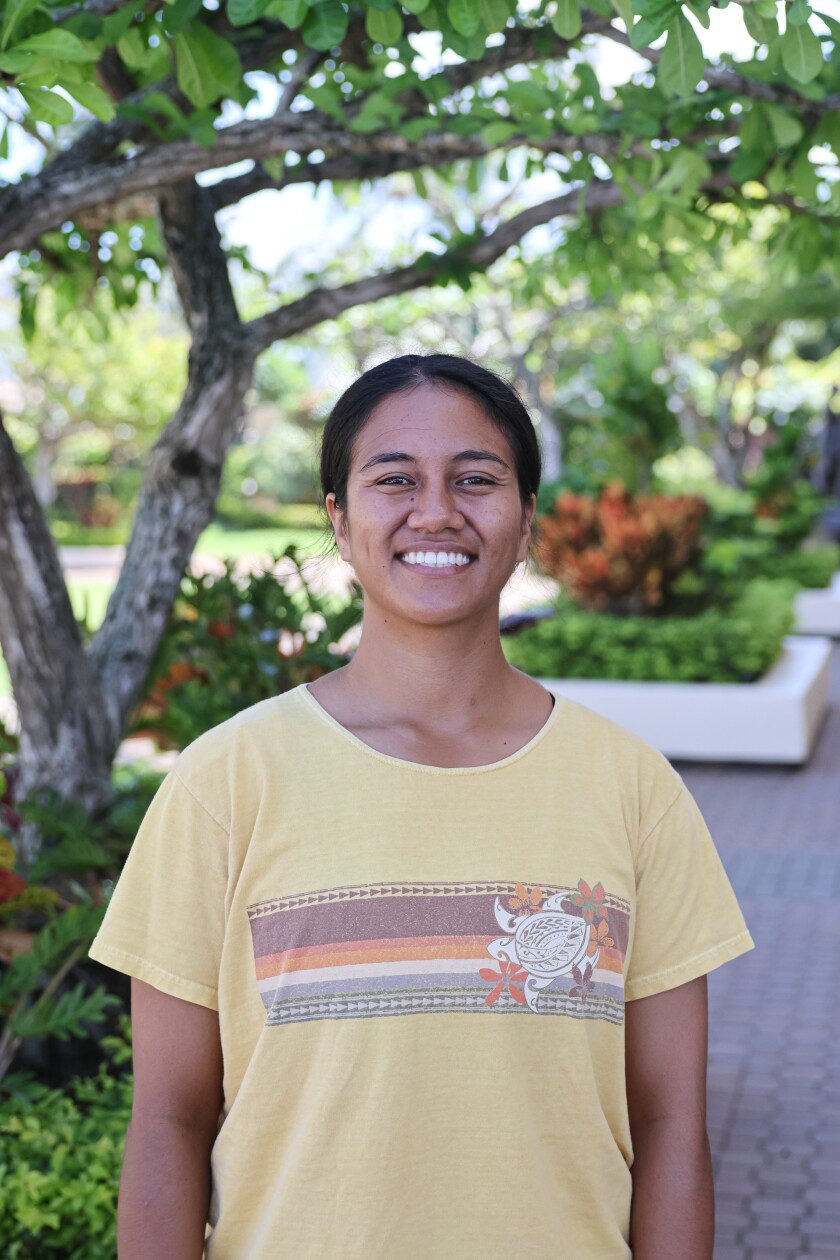 A woman smiles and poses for a photo outside.