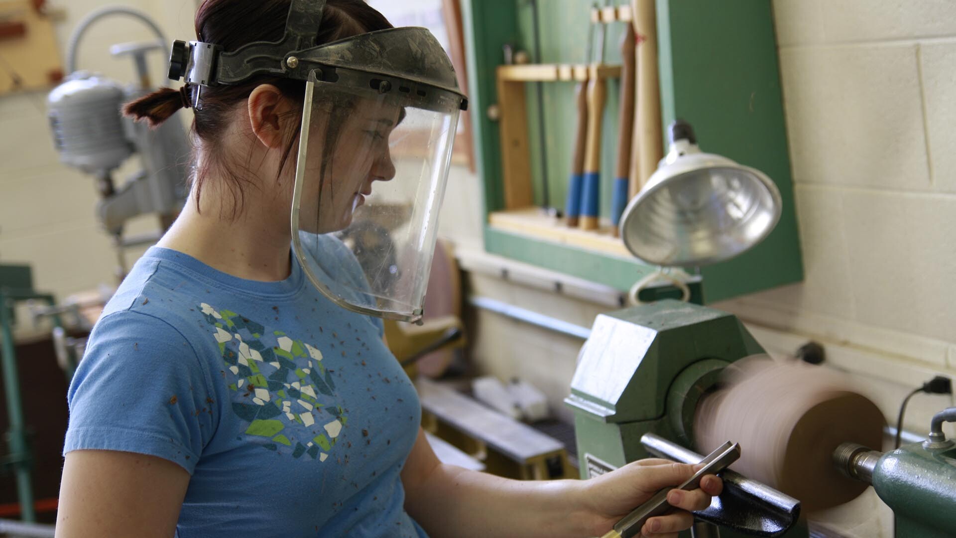 A female student using a wood working machine